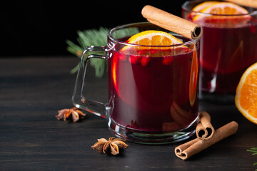 Two glasses with hot mulled wine with orange and spices on a wooden background. Hot drinks of...