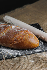 Top view of homemade bread with flour, natural agricultural products. Healthy and tasty pastries. Whole grain bread, flour. Close up, dark background