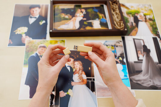 printed wedding photos, a wooden box and hands with a flash drive