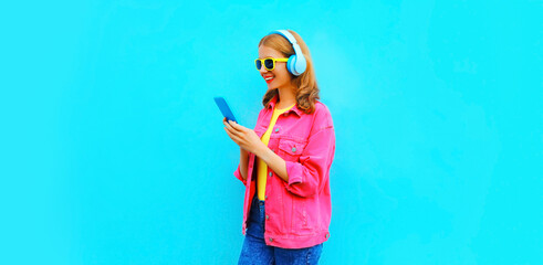 Portrait of stylish modern happy smiling young woman in headphones listening to music with...