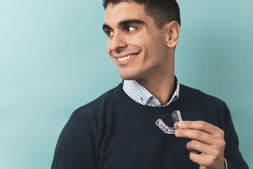 A man posing with resin splints for orthodontics. Mobile orthodontic appliance for dental correction. Placement of a bite plate in the mouth to prevent tooth death due to bruxism.