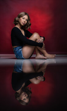 girl in red studio backdrop in jean shorts and reflective floor