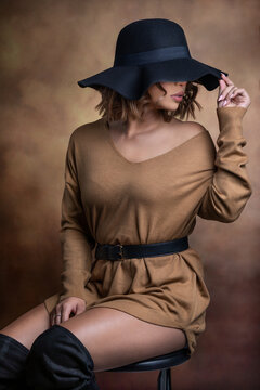 woman in black hat with brown cream outfit and backdrop