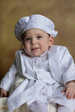 Smiling baby dressed in white clothes and brown fine art backdrop