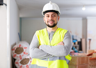 Portrait of a confident young builder standing on a construction site indoors