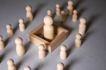 The child was lost in the crowd. A crowd of wooden figures of people surround a lost child.