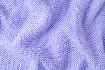 Close up background of knitted wool fabric made of viscose yarn. Bright purple color crumpled knitting wool knitwear texture. Abstract knitted wrinkled jersey fabric backdrop, wallpaper