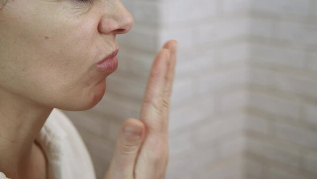 Odor in the mouth. Spray for halitosis. A woman with halitosis use spray for her mouth in the room.