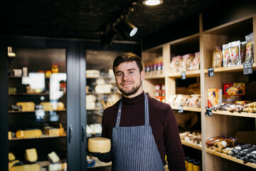 Fototapeta premium A man holds in hands cheese at the cheese factory. Blurred background.