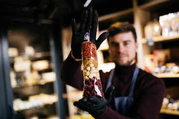 Dried fruits and nuts. Man holds the mix of nuts and raisins in bags. Wooden blurred background.