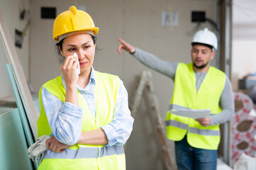 Asian woman engineer crying because she has been fired by her foreman who standing in background...