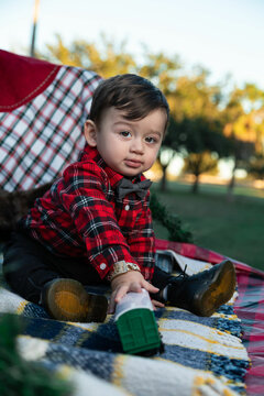 little child playing with Christmas train dressed in red flannel on christmas