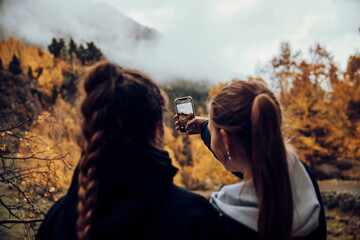 Friends taking a selfie with the mobile in the mountains in autumn