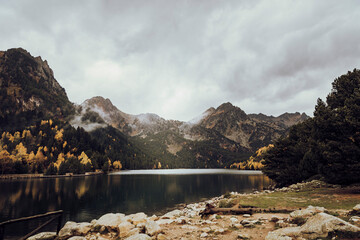 Mountain next to a lake and some trees during a cloudy day