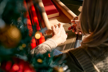 Wrapping christmas gifts. Blond woman wrapping presents in recycled card and decorated it with...