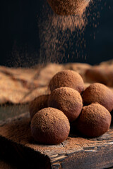 Pouring cocoa powder on enegry balls. Homemade Healthy vegan Raw Energy truffle Balls with on wooden cutting board.