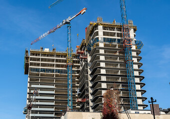 Construction site with cranes against blue sky. Industrial background. Modern skyscrapers. Unfinished construction