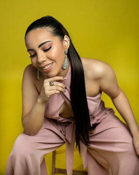 power portrait of a woman in pink jumper and yellow backdrop