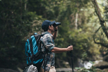 Hikers use binocular to see animals and view landscape  with backpacks in the forest. hiking and adventure concept.