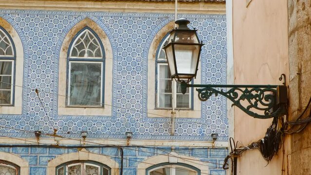 Close-up view of the typical tiled facades and a picturesque street lamp in Lisbon, two hallmarks of the Portuguese capital