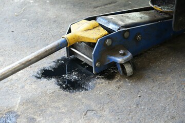 Black engine oil smeared on the floor under the jack.