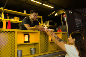 Smiling food truck cook serving fast food to a customer