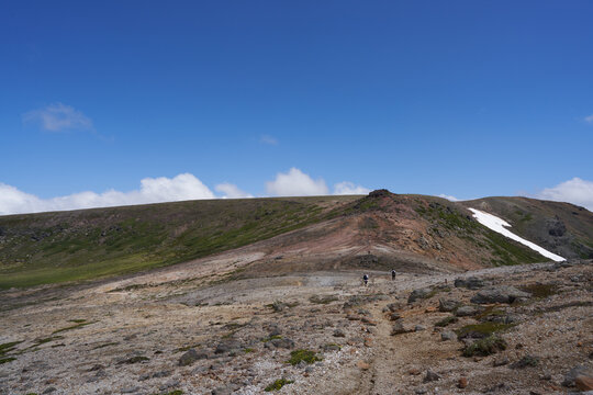 Two climbers walking on a rocky trail from Mt. Kumagadake to Mt. Mamiyadake