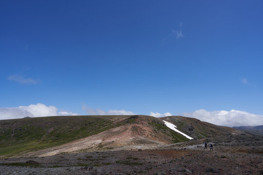 Two climbers walking on a rocky trail from Mt. Kumagadake to Mt. Mamiyadake