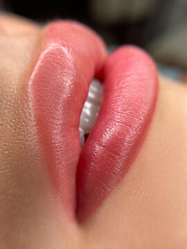 permanent makeup on the lips of a young woman of a delicate peach shade close-up, a girl after a cosmetic procedure with smooth and clean healthy skin.