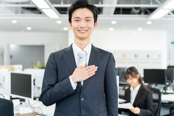 胸に手を当てる若いスーツを着た日本人男性