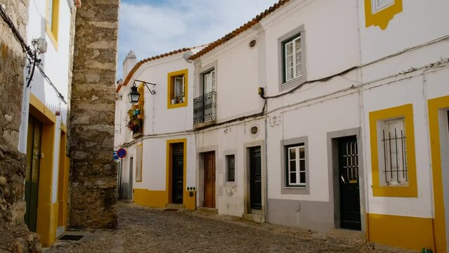 Discovering the narrow and picturesque streets of Evora, Portugal, featuring the famous whitewashed houses with yellow accents