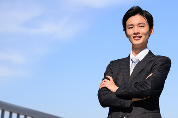 Asian businessman with arms crossed adjusting his collar　
