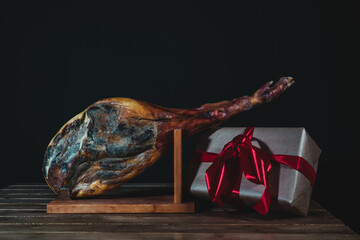 Spanish ham isolated on a black background with a gift box. Christmas