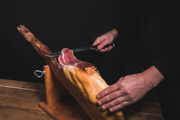 closeup chef cutting ham with knife.
