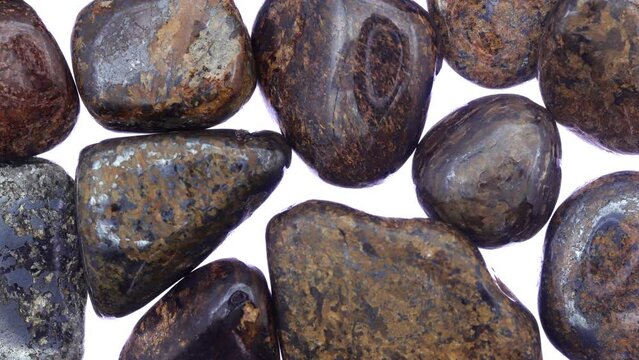 Bronzite heap jewel stones texture on white light background. Moving right seamless loop backdrop.