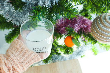 Woman's holding glass of milk with christmas tree.