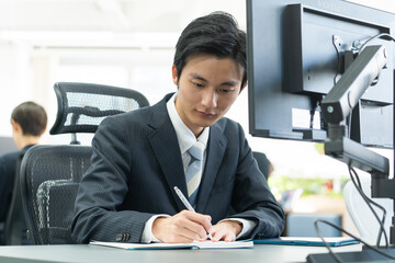 パソコンを見て学習する若いスーツを着たビジネスマン