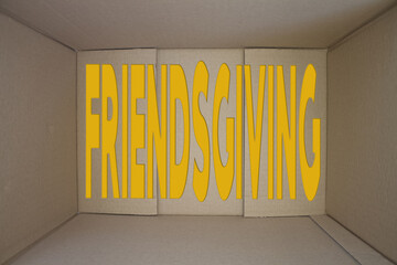 Friendsgiving word with cardboard box. Brown folded card box.