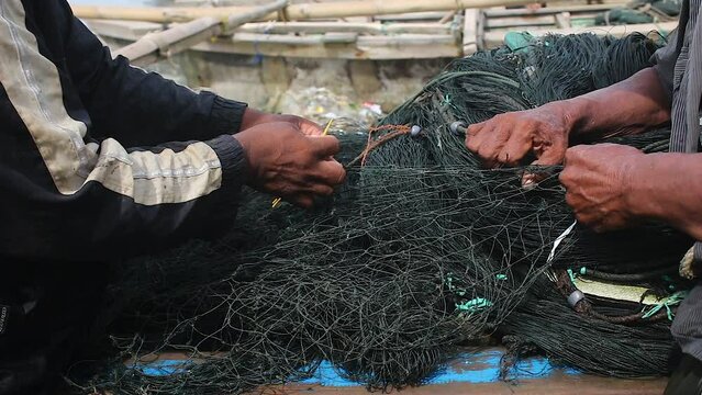 The hands of traditional fishermen are very skilled at embroidering fishing nets made of black nylon thread using needles made of bamboo.