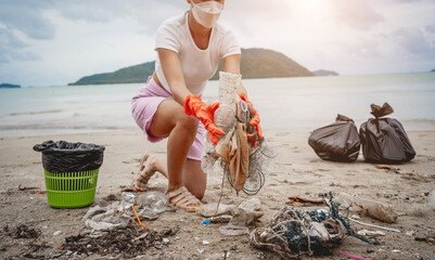 A female ecologist volunteer cleans the beach on the seashore from plastic and other waste