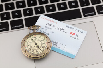 The pocket watch and a ticket are on the computer keyboard