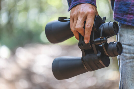 Hand Holding Binoculars Green Nature Bokeh Background.