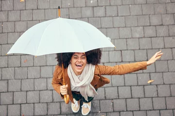 Fotobehang Black woman, umbrella and rain with smile, happy and enjoy weather in city being wet. Winter, young female and happiness for storm, cheerful and joyful with cover, comfortable and rainy outdoor. © David L/peopleimages.com