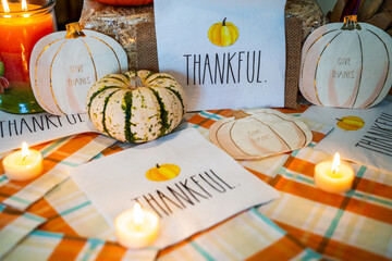 Thanksgiving table decorations to Give Thanks and Thankful greeting with pumpkins and candles to celebrate autumn and the Holiday season