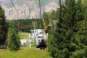 Summer mountain landscape high in the mountains. Tall trees of Christmas trees, ski lift at the ski...
