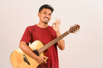 Portrait of Young Asian man in red t-shirt with an acoustic guitar isolated on white background