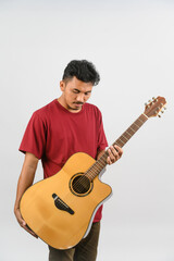 Portrait of Young Asian man in red t-shirt with an acoustic guitar isolated on white background
