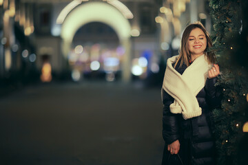 girl christmas lights evening decorated city, a young model on the background of urban decorations and garlands, night city lights