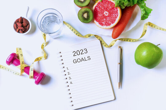 Flat lay of fruits, vegetables, dumbbell ,tape measure and a glass of water on white table. Clean eating and exercise for good health, 2023 goal concept. Top view, copy space for text