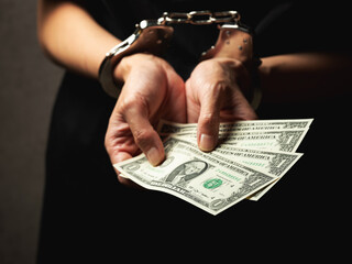 Handcuffs on wrists, dollar bills